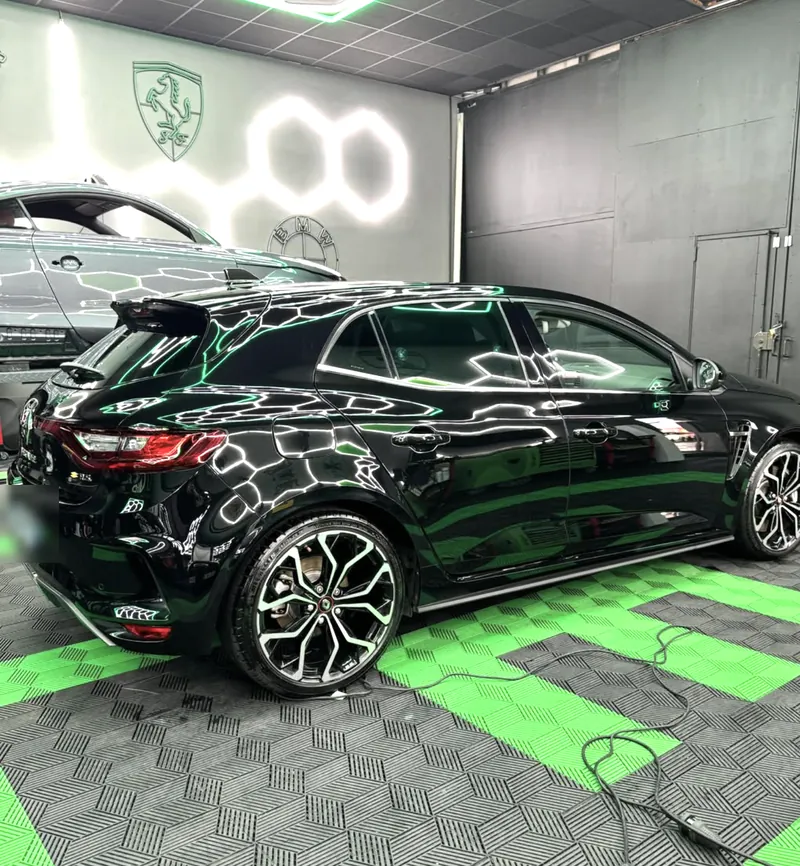 Renault Mégane IV RS noire polie, les néons du studio reflétés sur la carrosserie