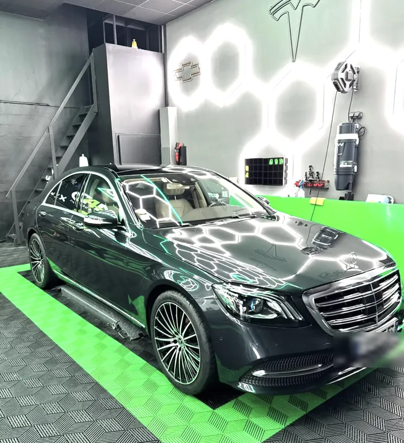Mercedes Classe S grise préparée avant la pose d'un film de protection, dans un studio aux néons hexagonaux