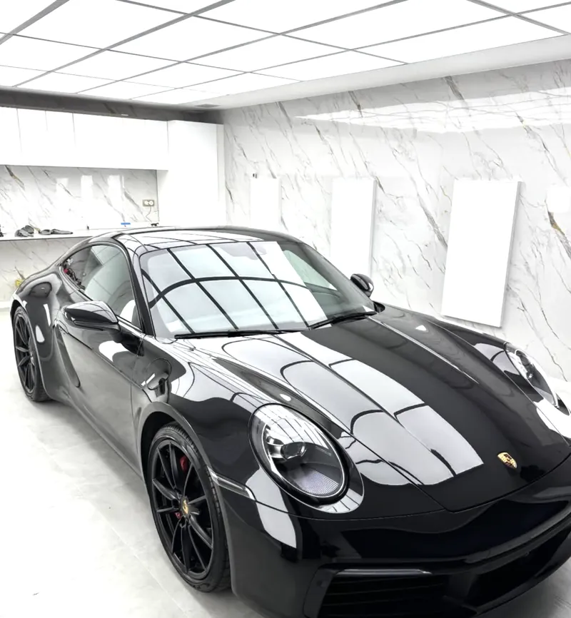 Porsche 992 noire après lustrage et céramique Gtechniq, dans un studio blanc aux panneaux lumineux